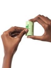 Hands holding a roll of compostable dog poop bags and tearing off a perforated sticker